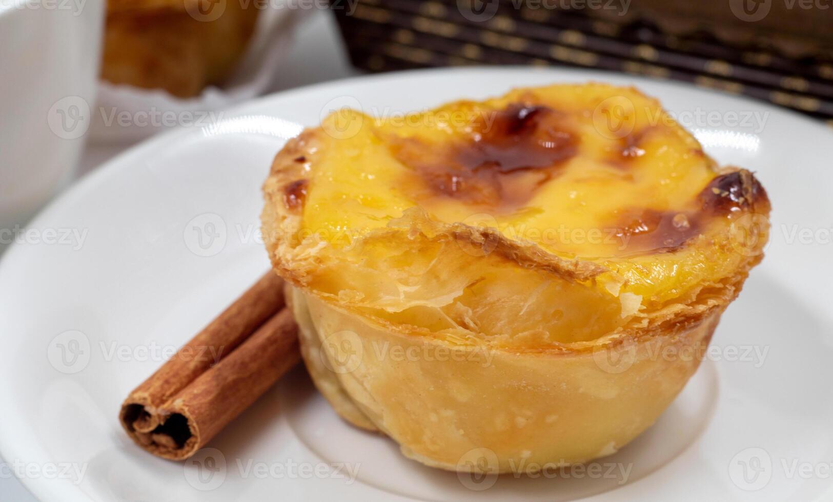 prato com 1 Português pastel de nata torta com creme e canela Gravetos. pastel de belém é a icônico em forma de xícara pastelaria com uma queimado topo e uma crocantes sopro pastelaria crosta. doce sobremesa. foto