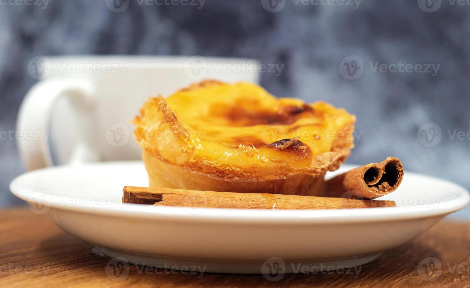 prato com 1 Português pastel de nata torta com creme e canela Gravetos. pastel de belém é a icônico em forma de xícara pastelaria com uma queimado topo e uma crocantes sopro pastelaria crosta. doce sobremesa. foto