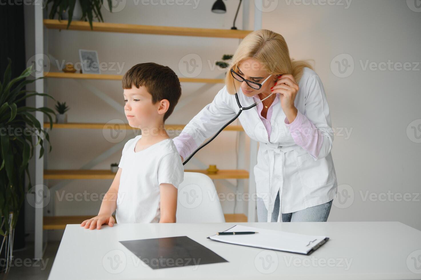 pediatra médico examinando pequeno Rapazes coração batida e pulmões para Verifica para problemas foto