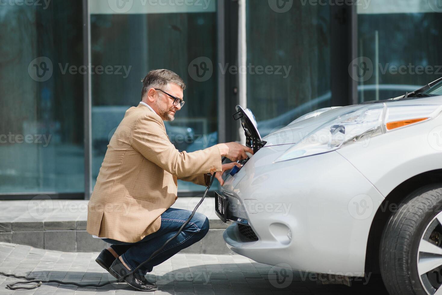 uma homem de negocios cobranças a elétrico carro foto