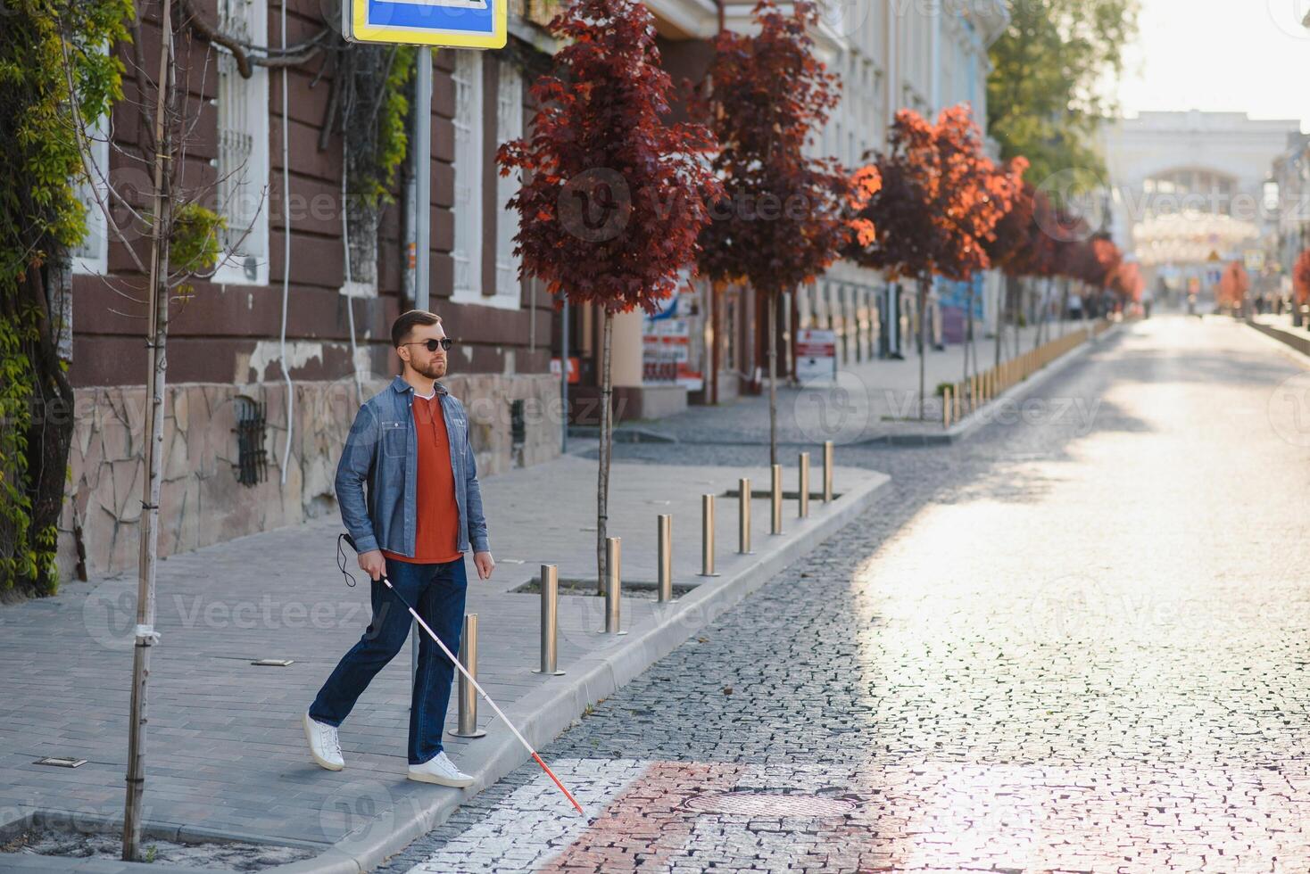 cego homem caminhando em calçada segurando bastão foto