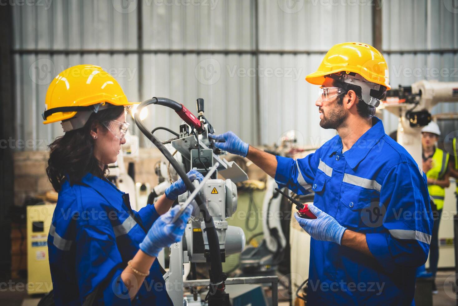 dois engenheiros mecânico usando computador controlador robótico braço para Soldagem aço dentro aço fábrica oficina. indústria robô programação Programas para automatizado fabricação tecnologia . foto