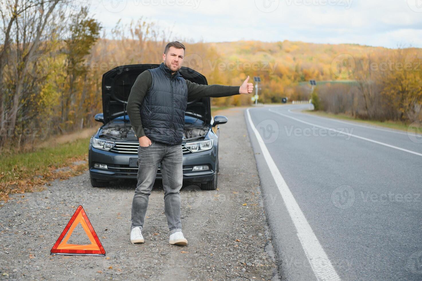 bonito jovem homem com dele carro quebrado baixa de a beira da estrada foto