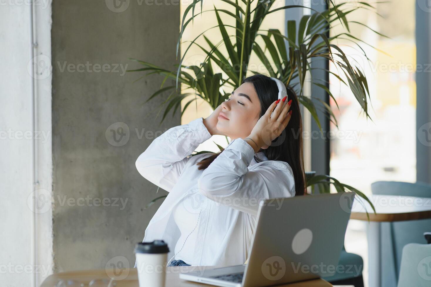 o negócio mulheres estilo de vida freelance sentado sozinho ele usando fones de ouvido ouvindo música Novo música durante trabalhando em computador portátil computador dentro café cafeteria comprar, aluna menina café pausa enquanto fazendo dever de casa foto