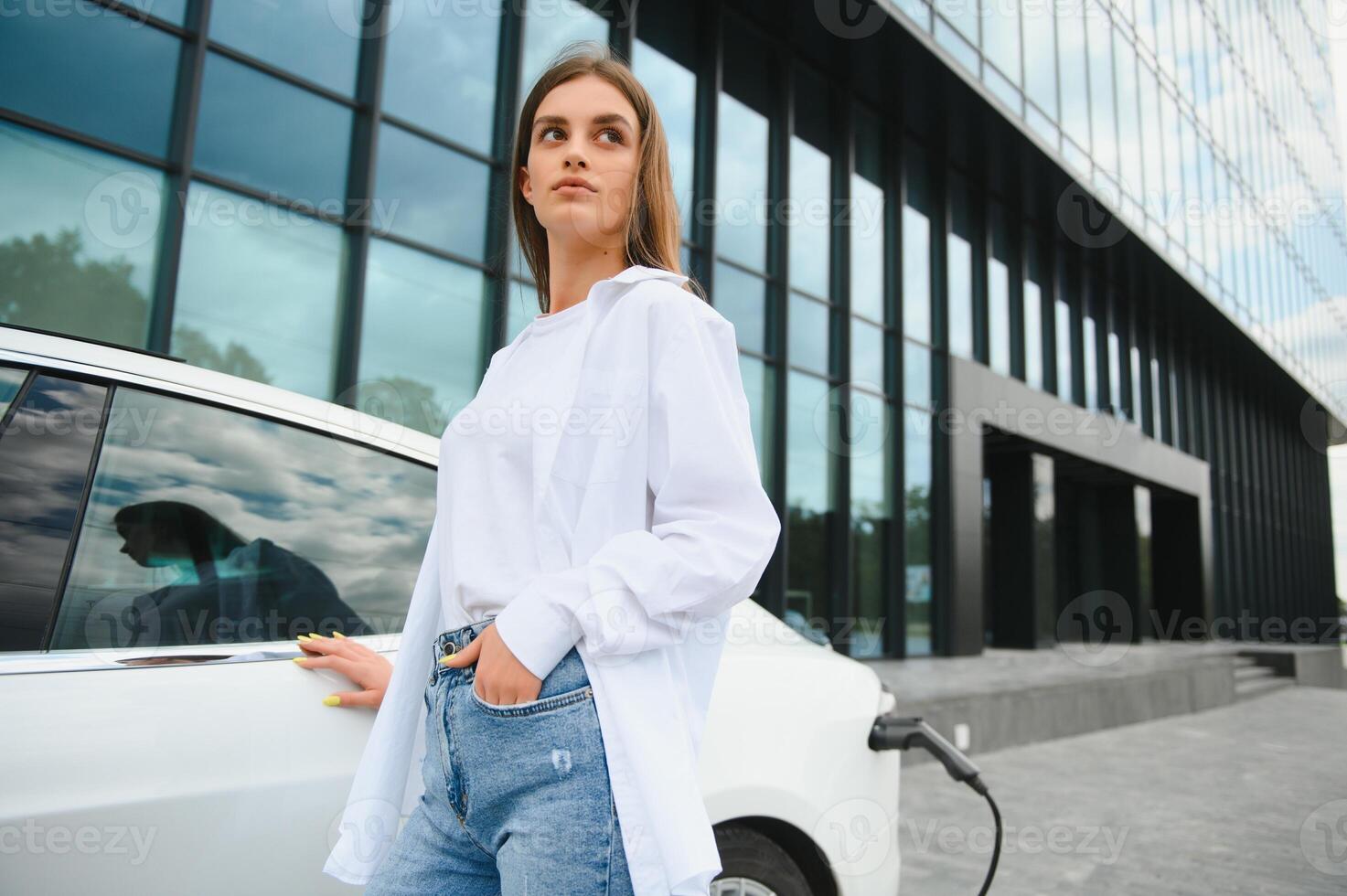 elétrico carro cobrando dentro rua. ecológico carro conectado e cobrando baterias. menina esperando poder fornecem conectar para elétrico veículos para carregando. foto