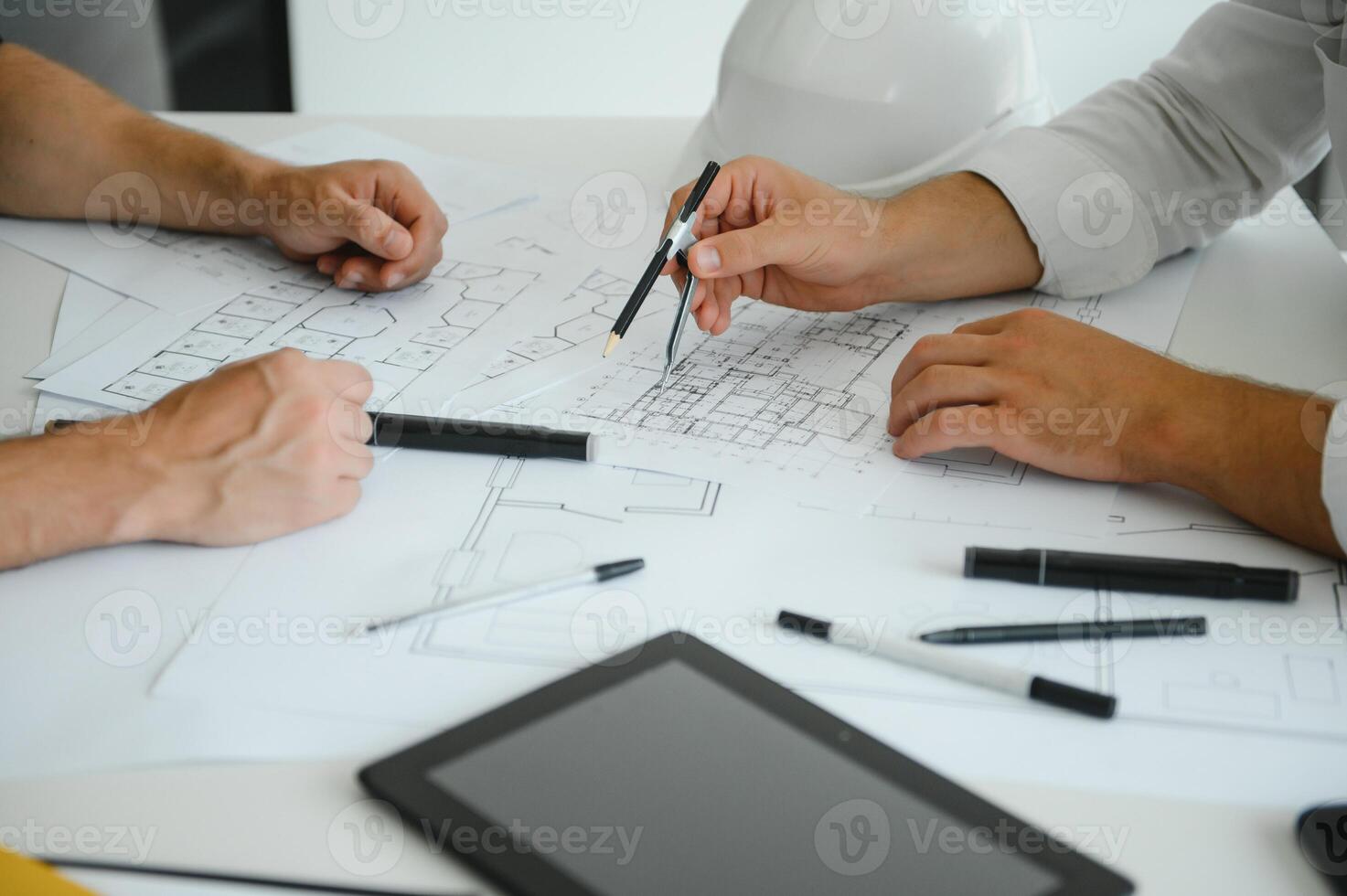 dois jovem arquitetos com plantas do uma casa em pé dentro escritório, conversando. foto