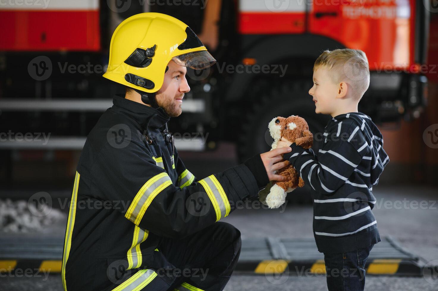 retrato do resgatado pequeno Garoto com bombeiro homem em pé perto fogo caminhão. bombeiro dentro fogo brigando Operação. foto