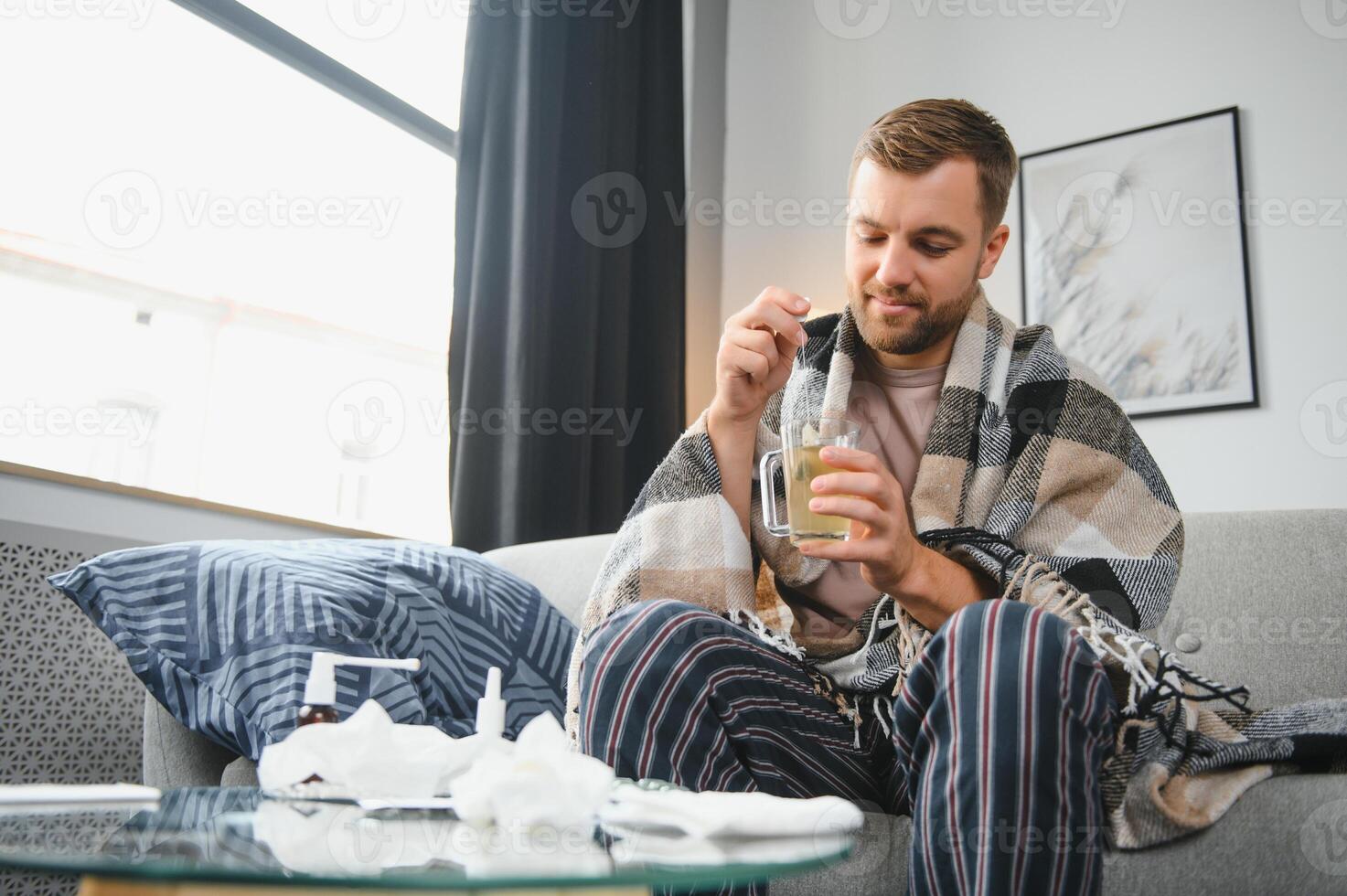 jovem doente barbudo europeu homem às casa em cinzento sofá com cobertor. doença, proteção, coronavírus, vírus, doença, gripe foto