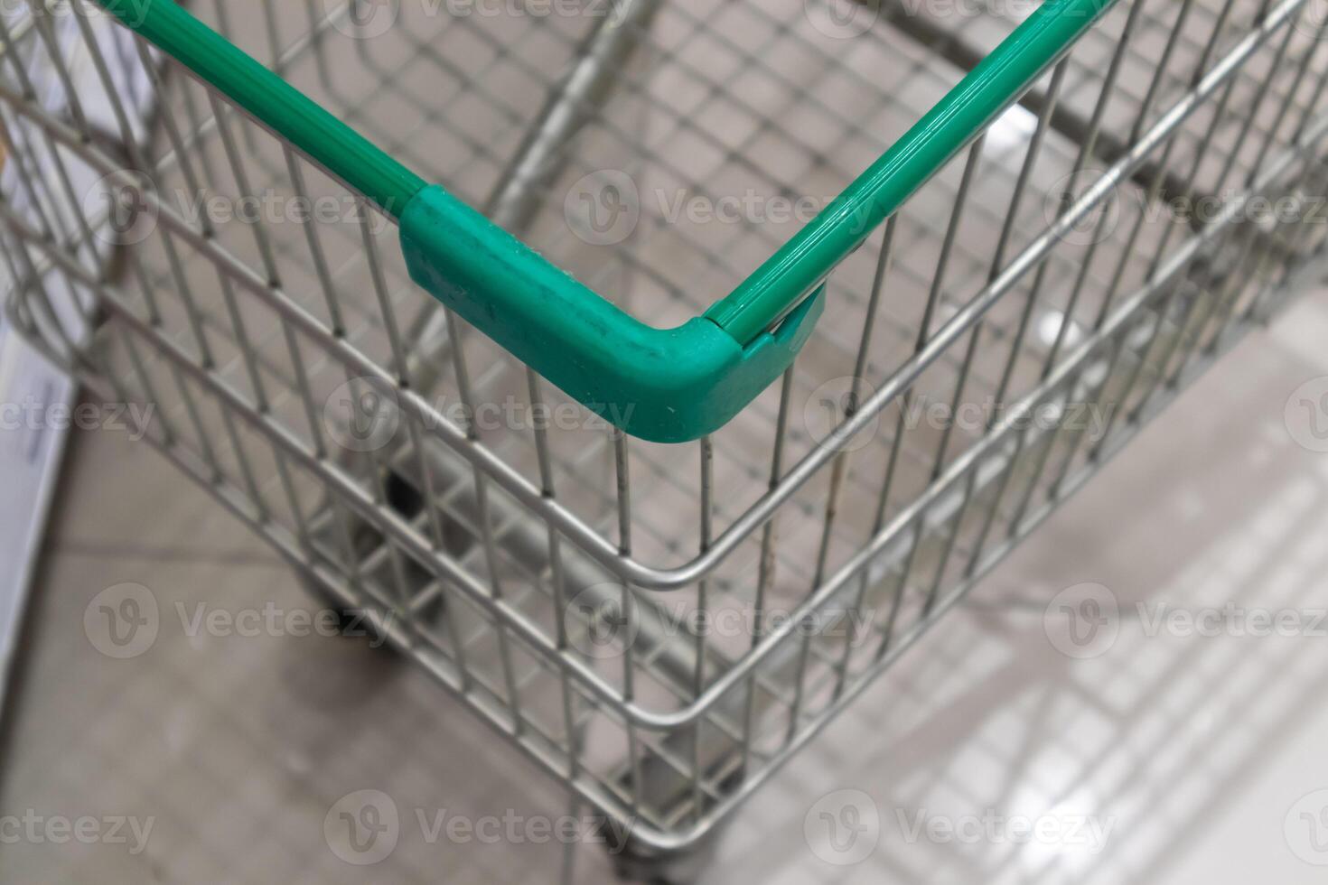 carrinho de compras verde vazio no corredor do supermercado foto