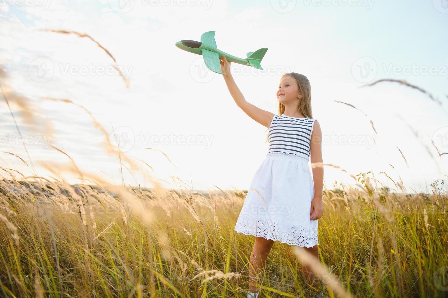 feliz menina corre com uma brinquedo avião em uma campo dentro a pôr do sol claro. crianças jogar brinquedo avião. adolescente sonhos do vôo e tornando-se uma piloto. menina quer para tornar-se uma piloto e astronauta. lento movimento. foto