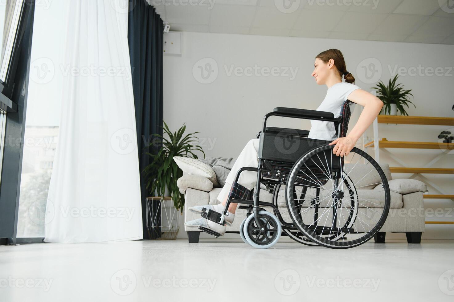 mulher olhando longe enquanto sentado dentro cadeira de rodas às casa foto
