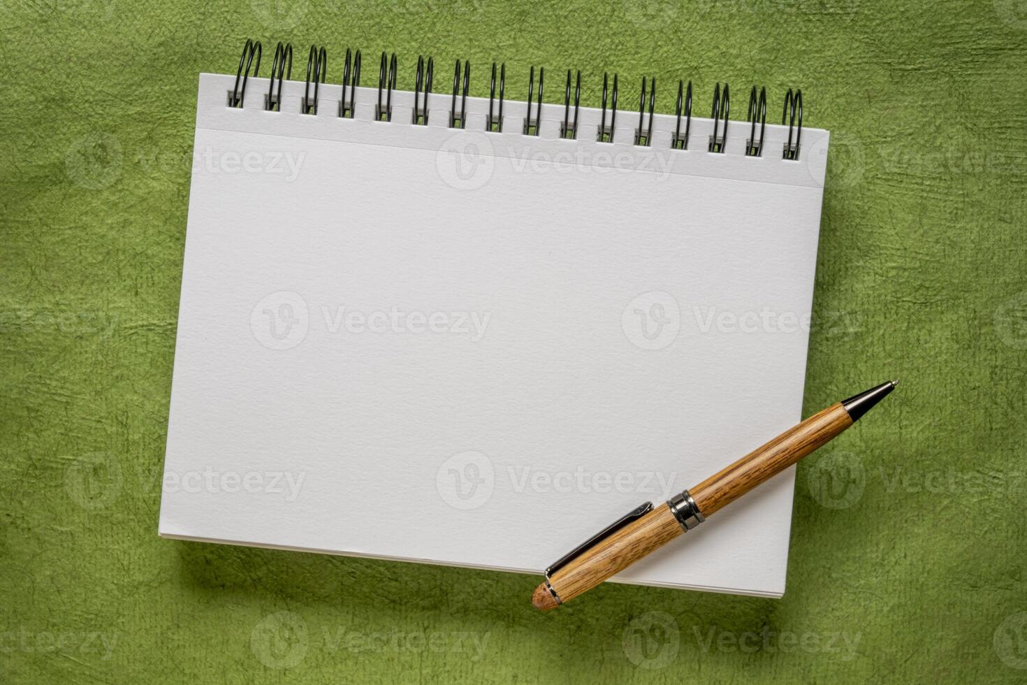 em branco espiral caderno com uma luxo de madeira caneta em verde texturizado arte papel foto