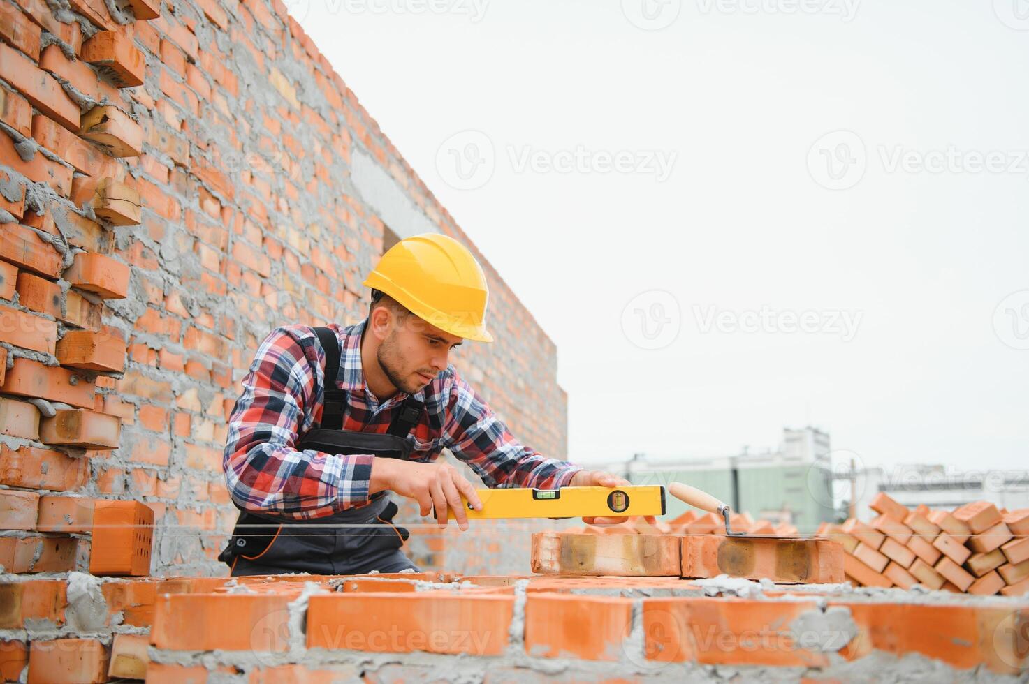 construção pedreiro trabalhador pedreiro instalando vermelho tijolo com espátula massa de vidraceiro faca ao ar livre. foto