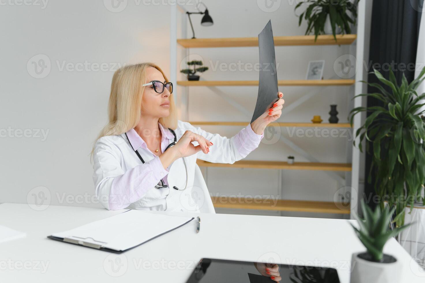 retrato tiro do meio envelhecido fêmea médico sentado às escrivaninha e trabalhando dentro médico escritório foto