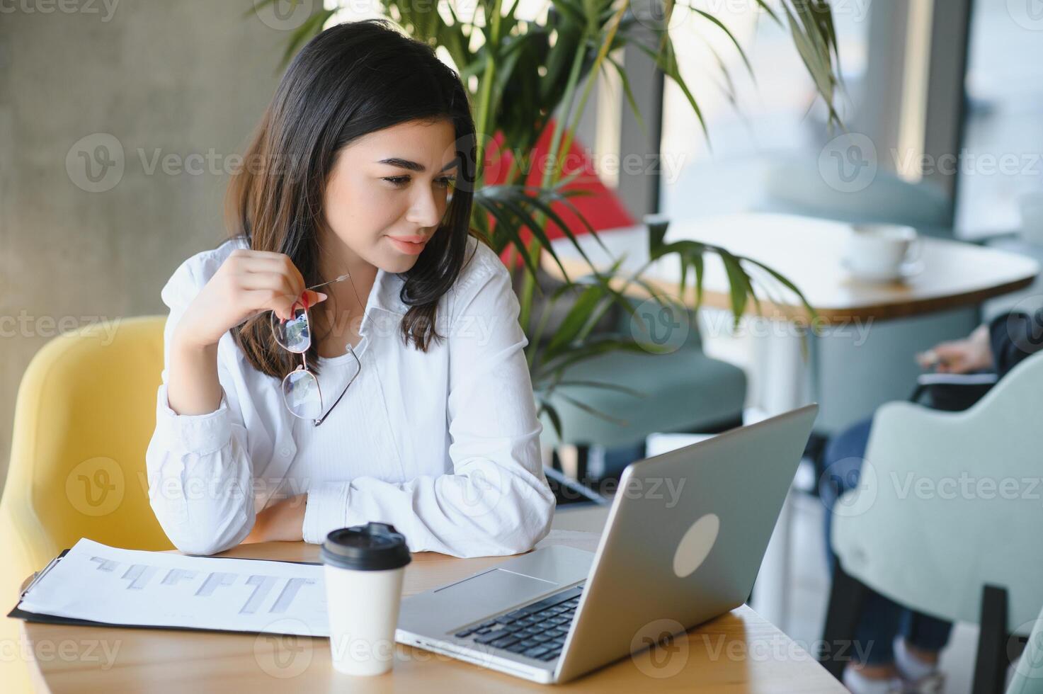 sorridente menina aluna estude conectados com skype professor, feliz jovem mulher aprender língua ouço palestra Assistir webinar escrever notas Veja às computador portátil sentar dentro cafeteria, distante Educação foto