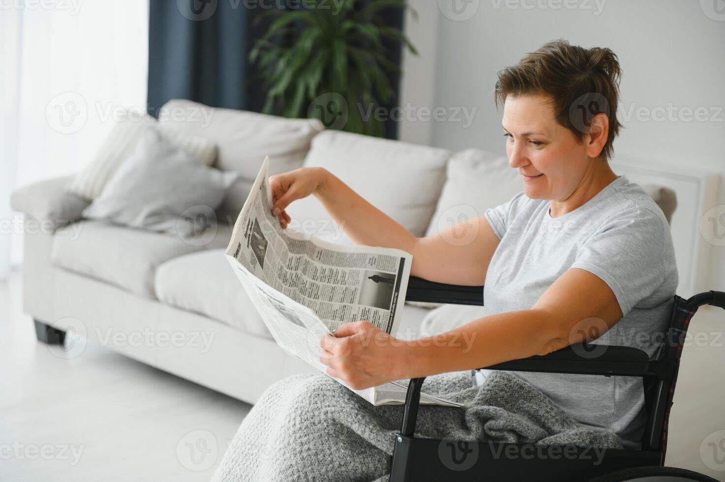 mulher dentro cadeira de rodas lendo jornal dentro de casa foto