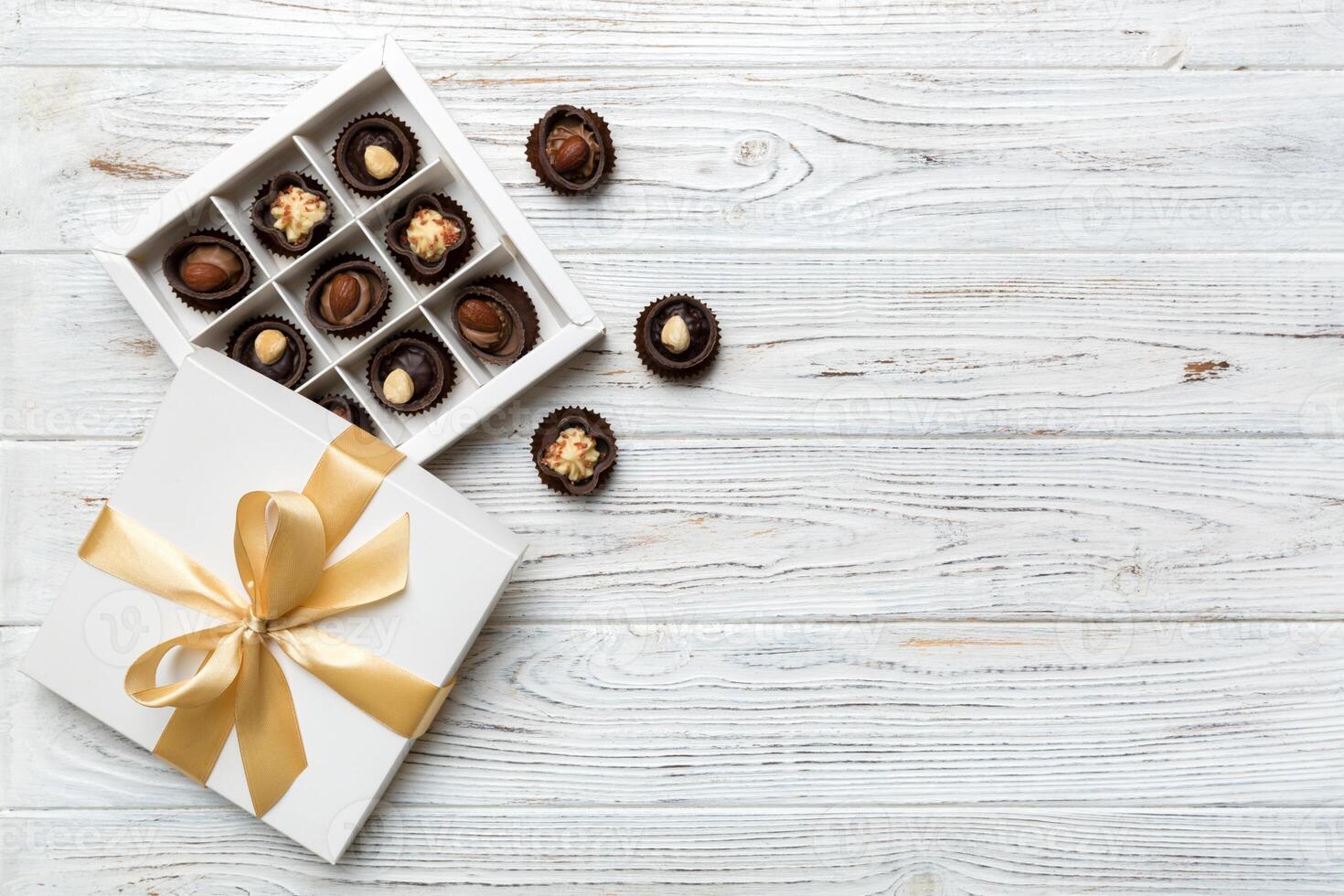 branco caixa com chocolates doces e dourado fita. topo Visão com cópia de espaço foto