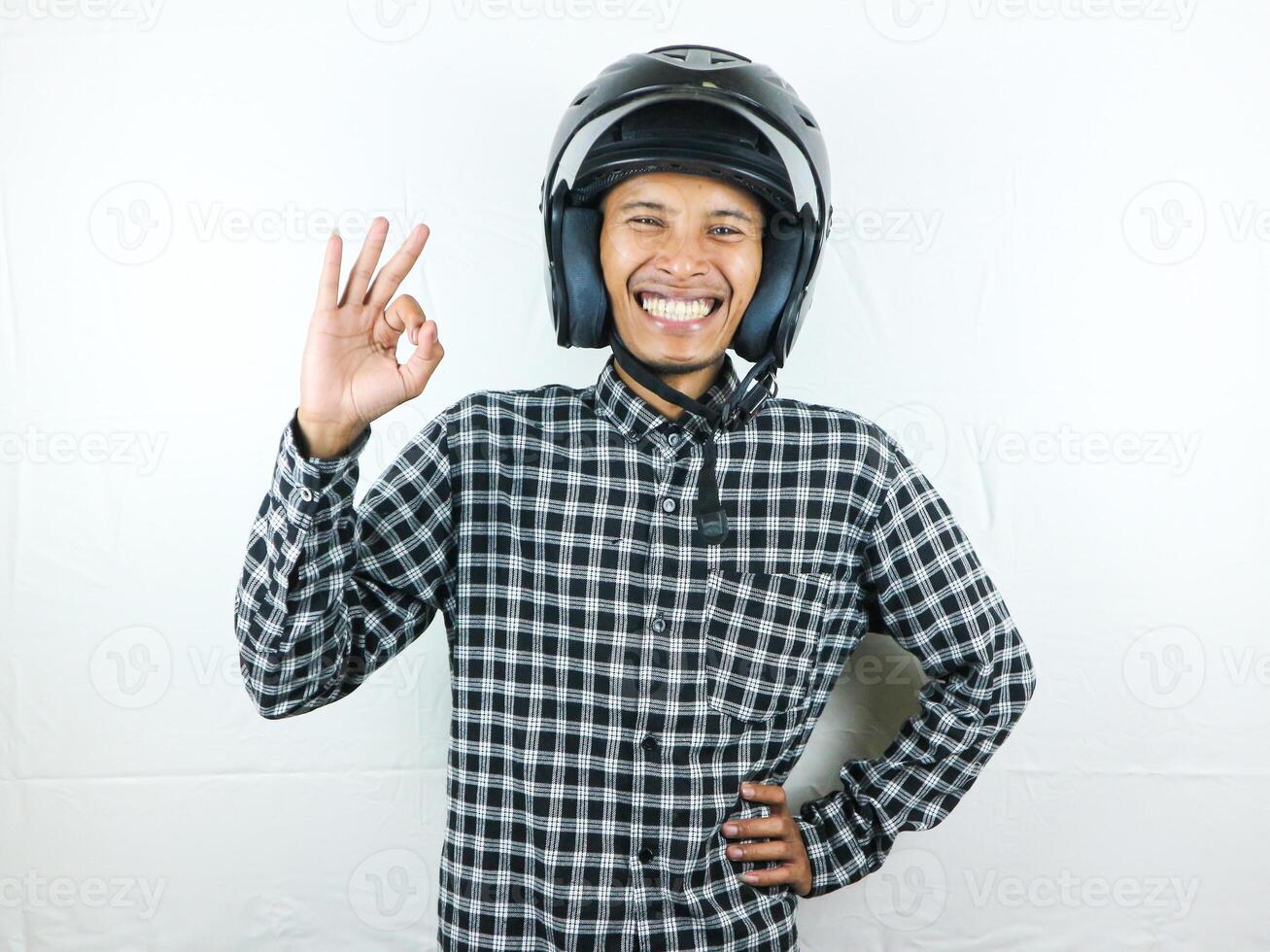 retrato ásia homem segurando motocicleta capacete com animado expressão. segurança cavalgando. foto