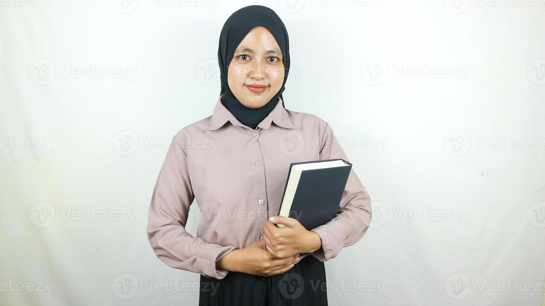 sorridente jovem ásia muçulmano aluna segurando livro, olhando às Câmera isolado em branco fundo. foto