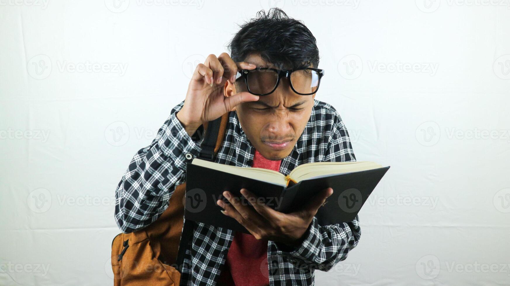 bonito ásia aluna sorridente e segurando e lendo livro dentro mão foto