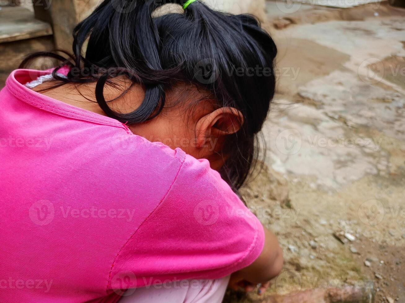 uma pequeno menina envelhecido 3-4 anos abaixado dela cabeça e coberto dela face com dela mãos. conceito foto do social problemas, família, violência contra crianças e criança Abuso.