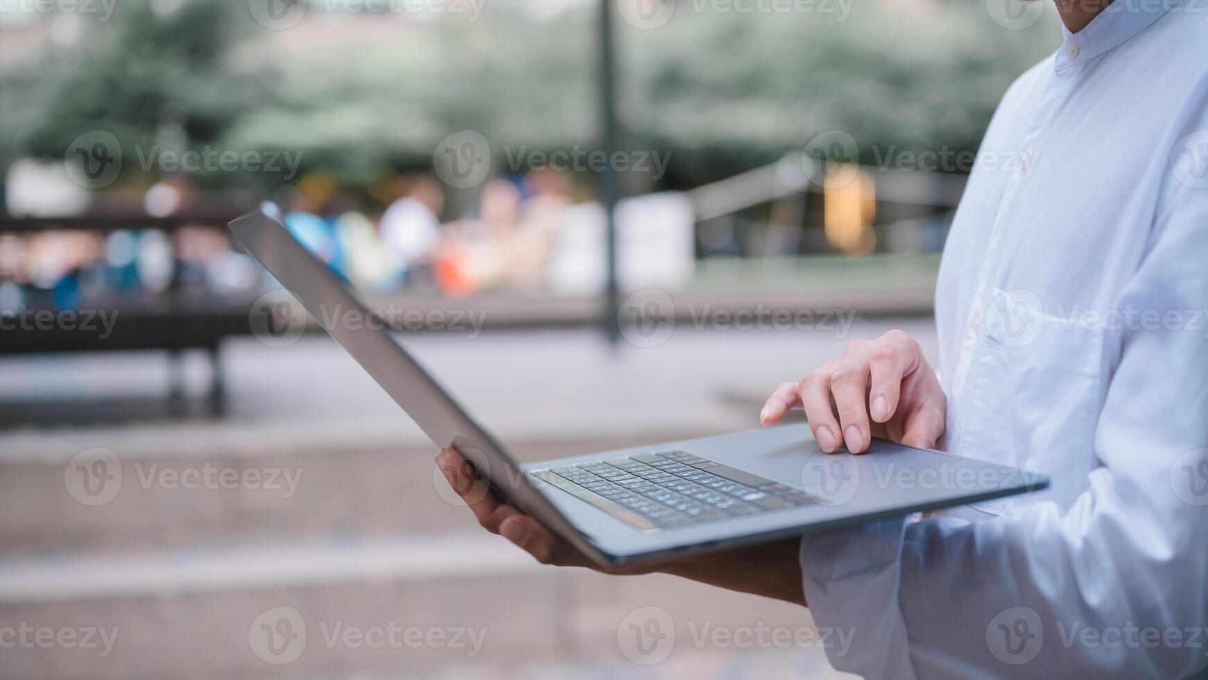 uma homem de negocios ou trabalhador autonomo usando computador computador portátil sentado em mesa lado de fora trabalhando em o negócio ou Internet conectados marketing foto