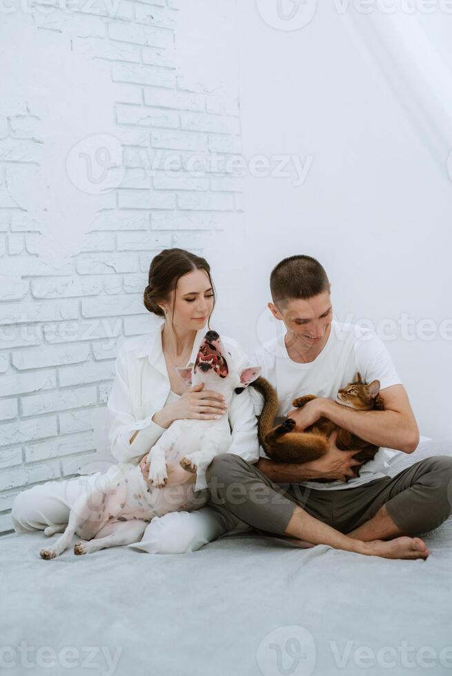 jovem casal cara e menina dentro uma brilhante quarto jogando com animais de estimação foto