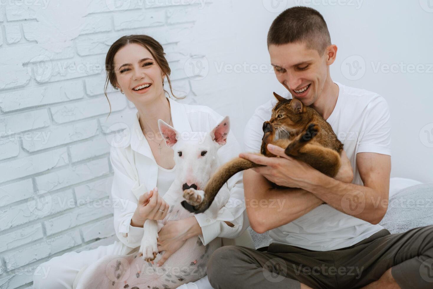 jovem casal cara e menina dentro uma brilhante quarto jogando com animais de estimação foto