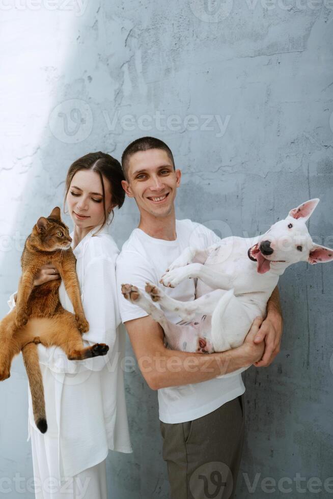 jovem casal cara e menina dentro uma brilhante quarto jogando com animais de estimação foto