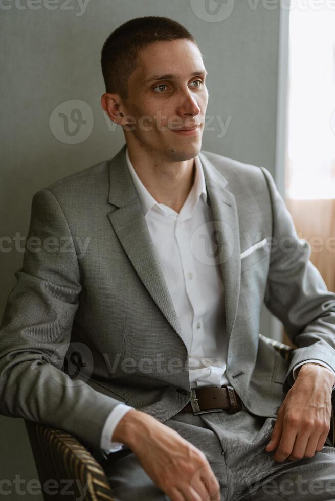 retrato do uma noivo dentro uma cinzento xadrez terno com uma gravata dentro uma luz Barra foto