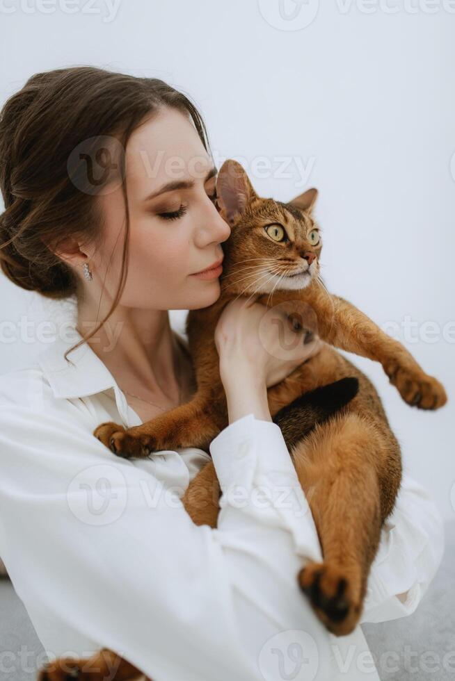 jovem menina dentro uma branco quarto jogando com uma gato foto