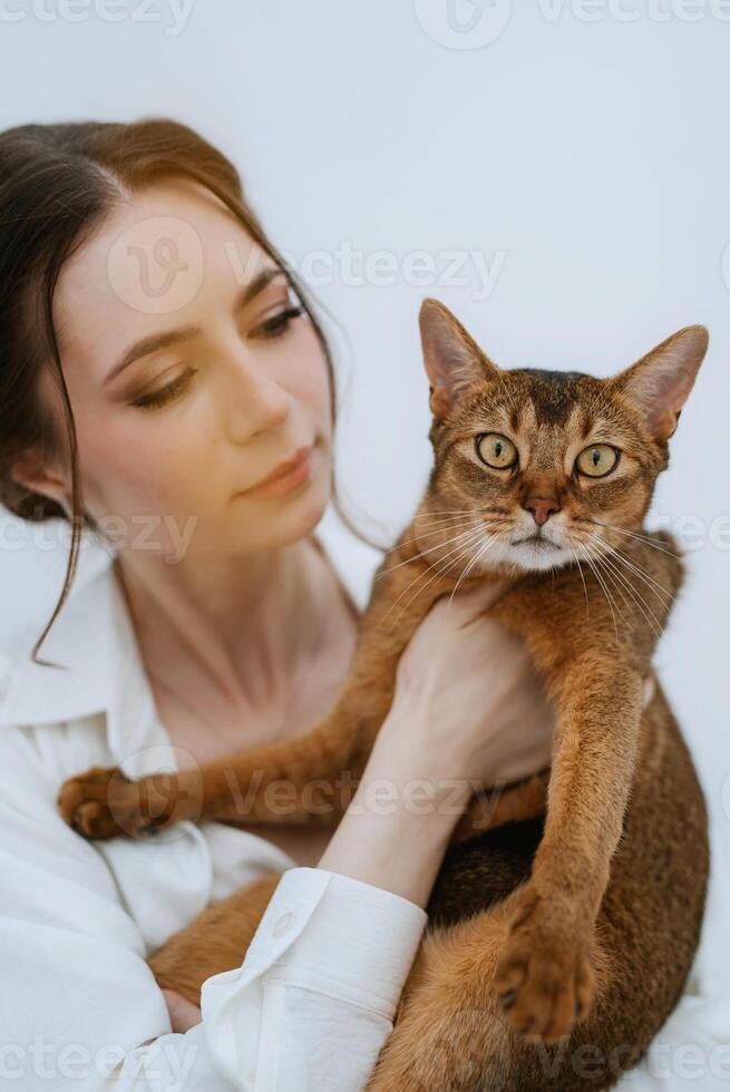 jovem menina dentro uma branco quarto jogando com uma gato foto