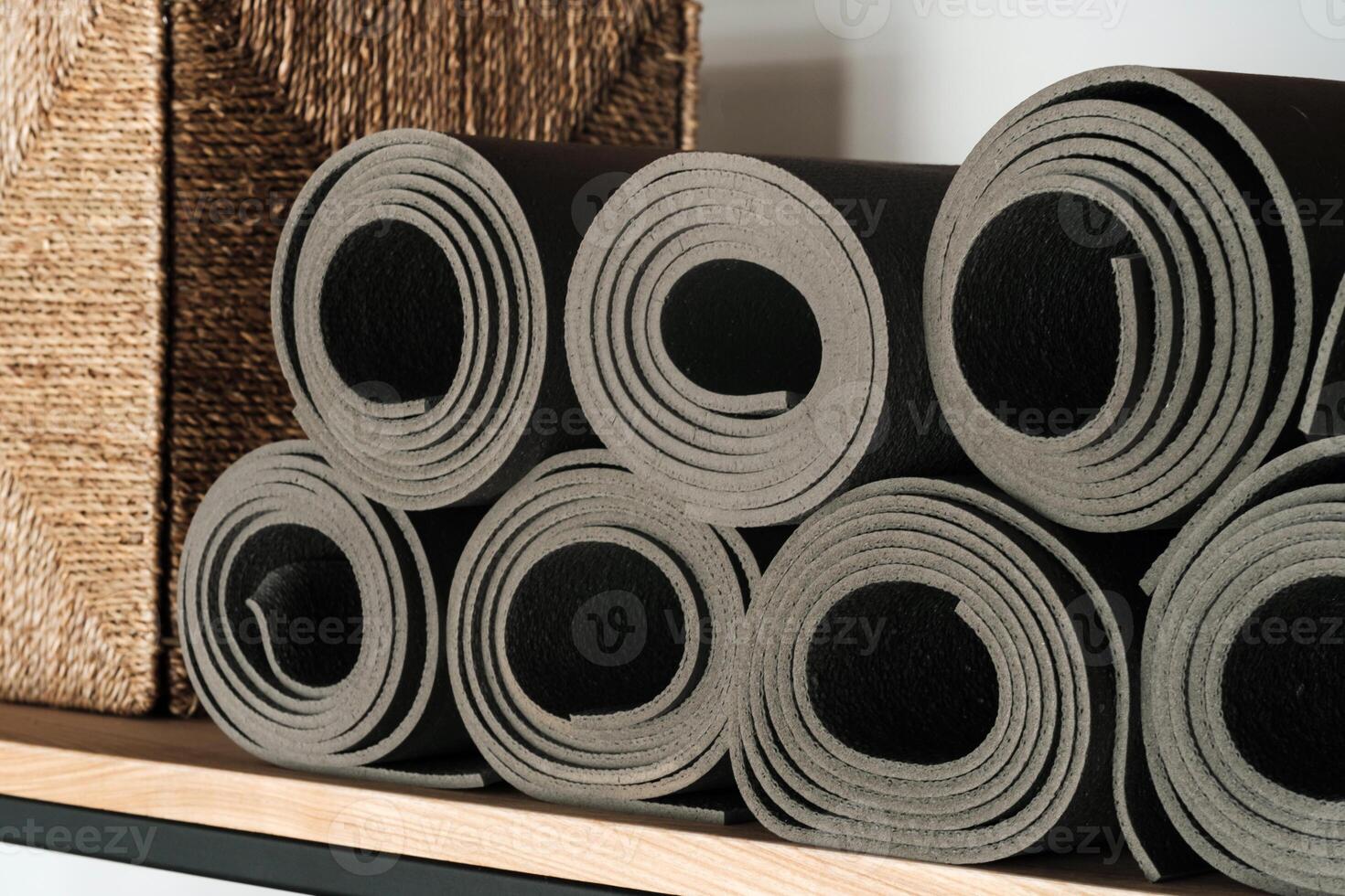 cinzento ioga tapetes deitado em uma prateleira, enrolado acima foto