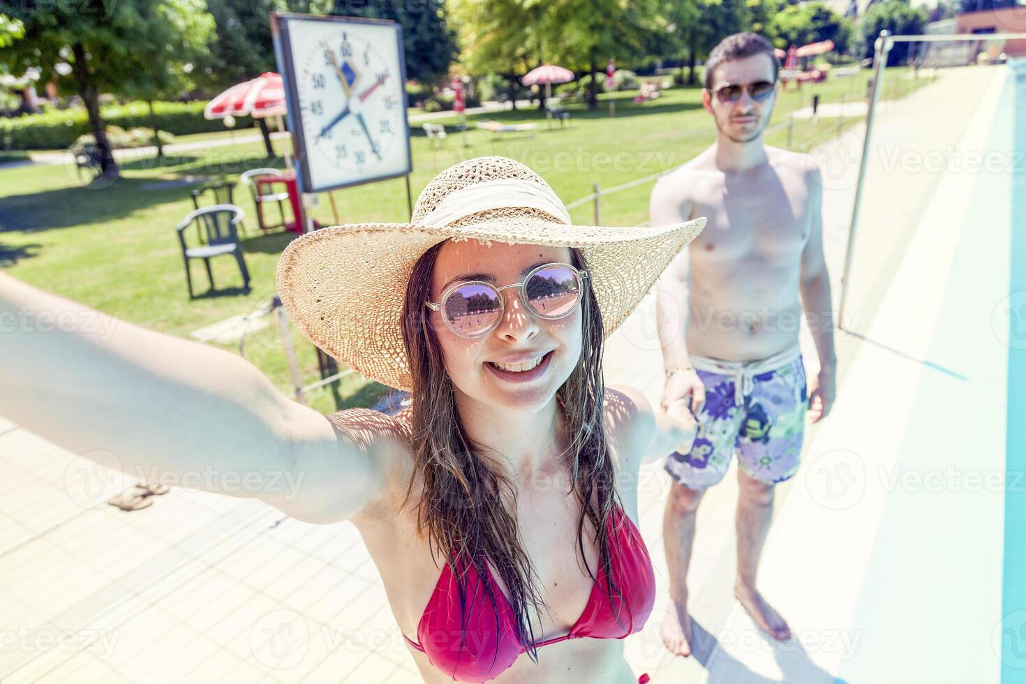 jovem amoroso casal ao lado a piscina leva uma selfie foto