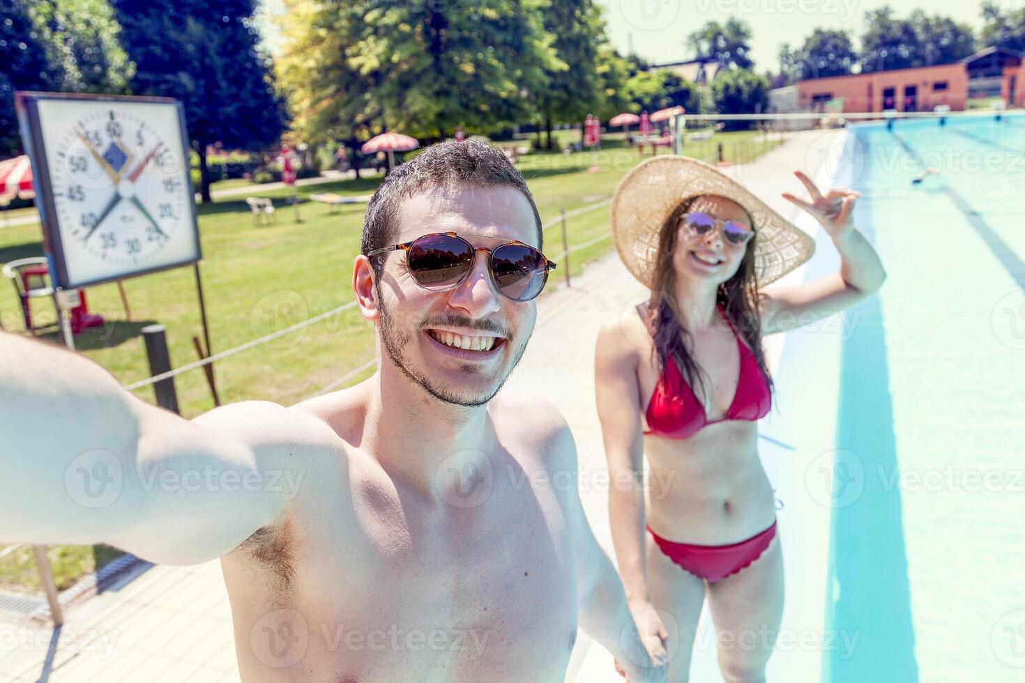 jovem amoroso casal ao lado a piscina leva uma selfie foto