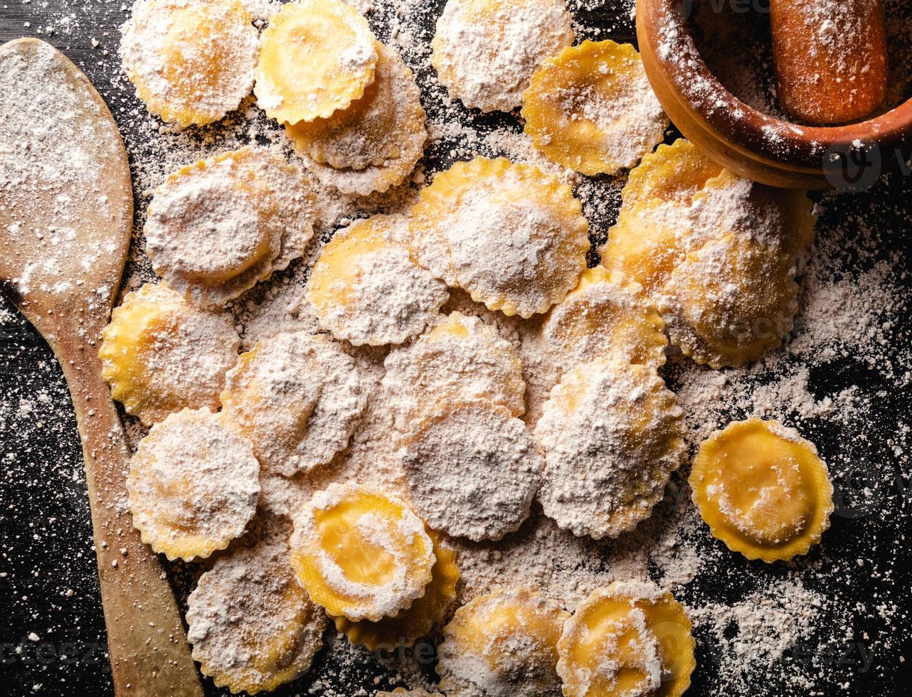 saboroso ravioli cru com farinha e manjericão na mesa de madeira foto