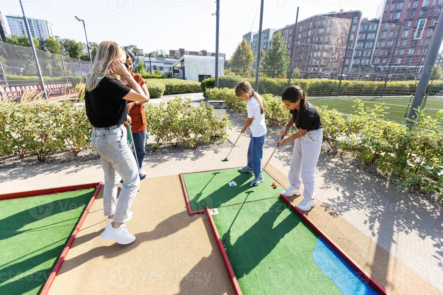 fofa escola menina jogando mini golfe com família. feliz criança pequena criança tendo Diversão com ao ar livre atividade. verão esporte para crianças e adultos, ao ar livre. família Férias ou recorrer. foto