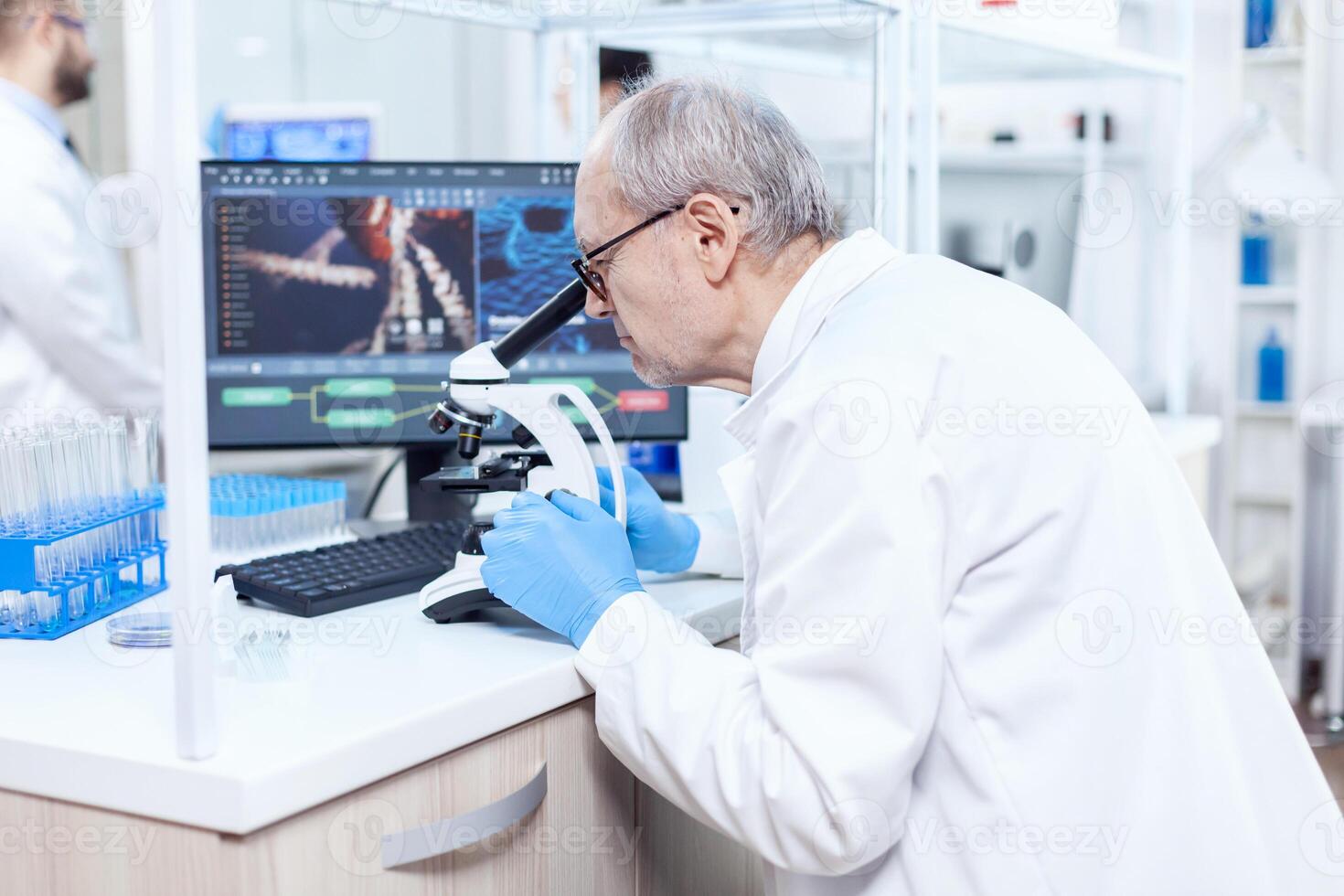 Senior caucasiano cientista microbiologia laboratório conduzindo vírus análise olhando através microscópio. químico investigador dentro estéril laboratório fazendo experimentos para médico indústria usando moderno tecnologia. foto