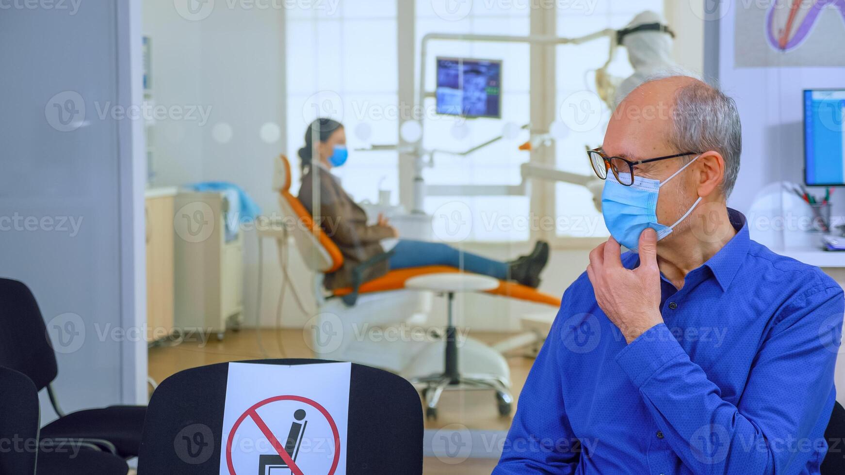 retrato do idosos paciente com proteção mascarar falando sentado em cadeiras guardando social distância dentro estomatológico clínica, esperando para médico durante coronavírus. conceito do Novo normal dentista Visita foto