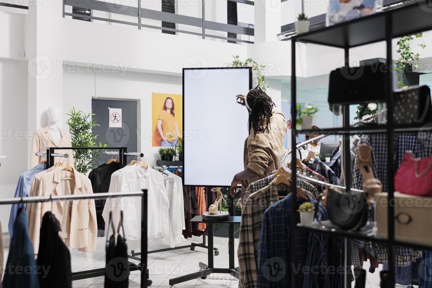 cliente pressionando em inteligente quadro branco toque tela dentro roupas departamento fazer compras. africano americano homem usando interativo borda com em branco exibição para ler sobre fêmea sapatos dentro moda loja foto