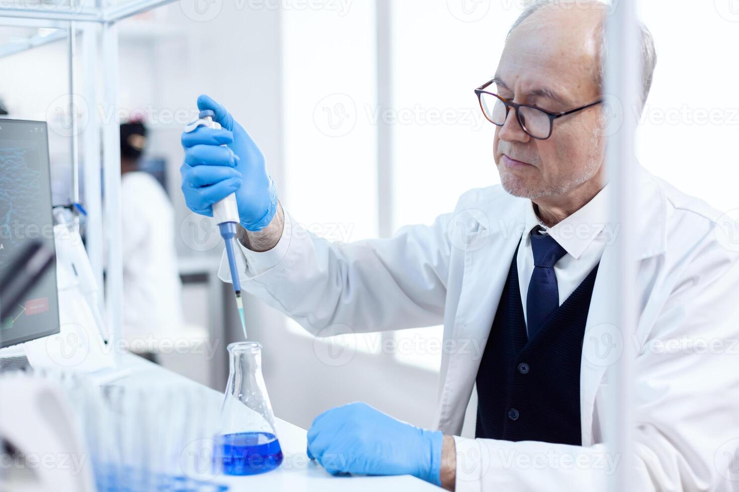 idosos cientista fazendo genético experimentar dentro ocupado laboratório usando estéril conta-gotas com azul líquido. Senior profissional químico usando pipeta com azul solução para microbiologia testes. foto