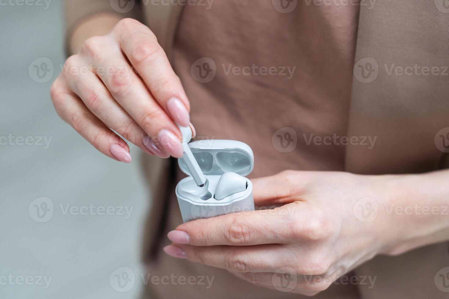 branco sem fio fones de ouvido no ouvido ou fone de ouvido Bluetooth com cobrando caso segurando dentro mão isolado em branco fundo. fechar-se do Novo tecnologia branco pequeno fone de ouvido sem fio. foto