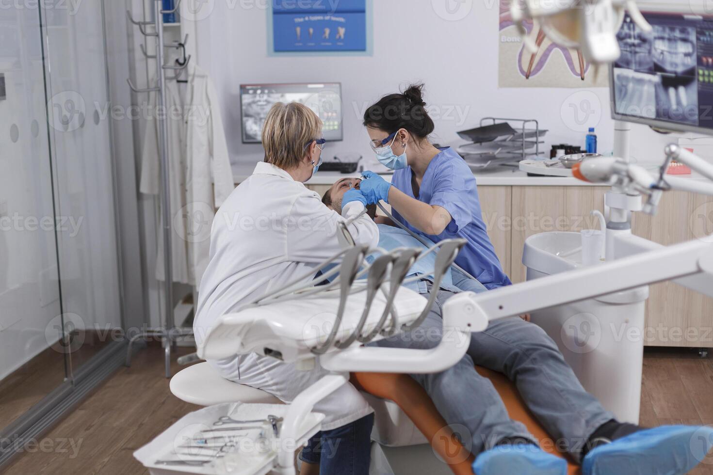 ortodontista equipe com médico face máscaras trabalhando às paciente dentes discutindo oral higiene durante estomatológico consulta dentro odontologia escritório sala. conceito do estomatologia procedimento foto