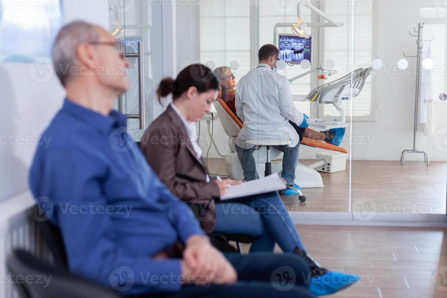 Senior mulher sentado em cadeira dentro dental escritório ouvindo dentista falando sobre diagnóstico para dentes cavidade olhando às digital raio X radiografia. pacientes o preenchimento Formato dentro esperando área. foto