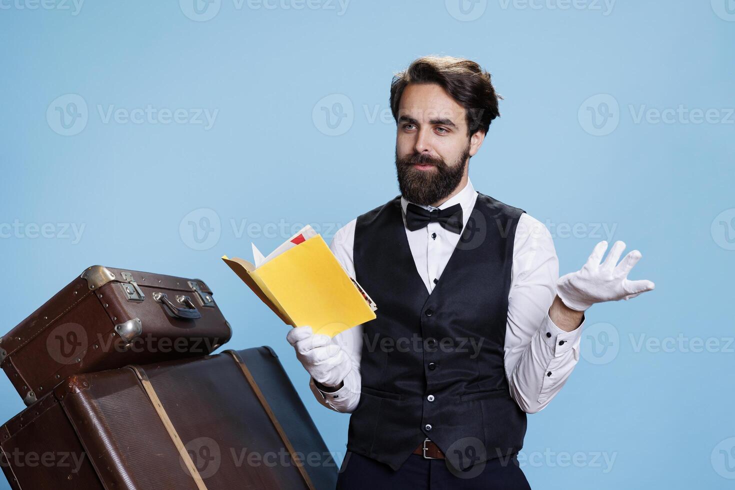 masculino mensageiro lê Novo história a partir de livro, tendo Diversão com elegante passatempo dentro estúdio. profissional porteiro dentro terno e gravata lendo literatura ou ficção em Câmera, hotel indústria ocupação. foto