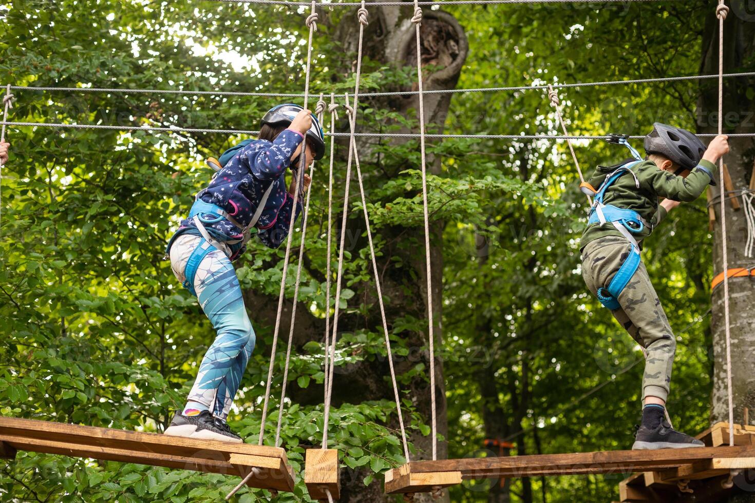 adorável pequeno menina desfrutando dela Tempo dentro escalada aventura parque em caloroso e ensolarado verão dia. foto