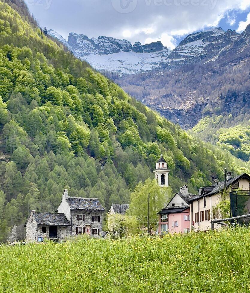uma Vila dentro a montanhas com uma Igreja e verde árvores foto