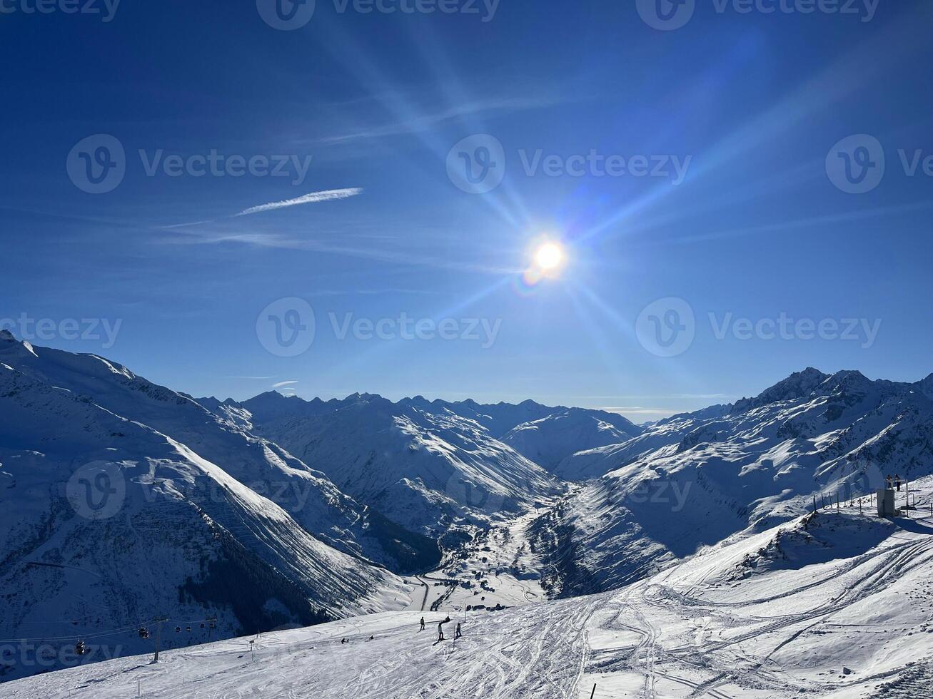 a Sol brilha brilhantemente sobre uma Nevado montanha alcance foto