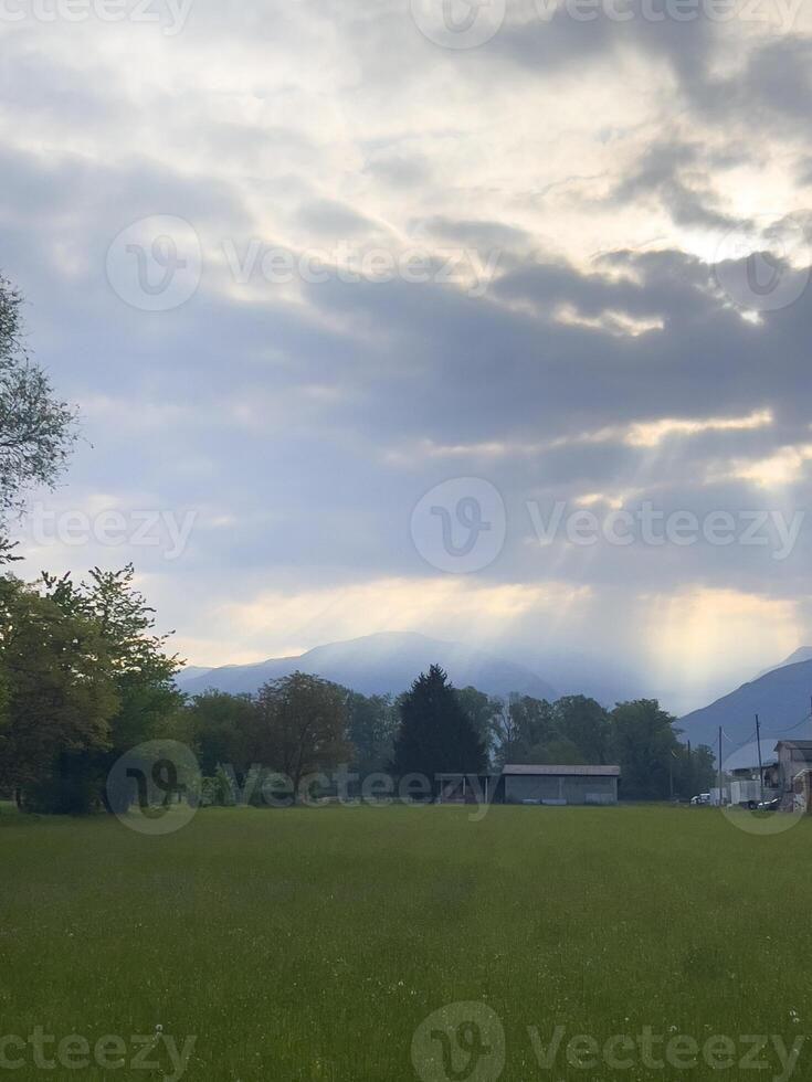 uma campo com uma casa e montanhas dentro a fundo foto