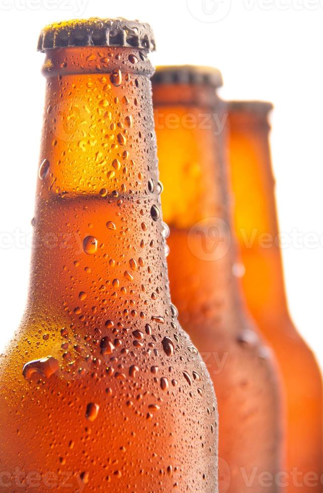 três garrafas de cerveja fresca em fundo branco foto